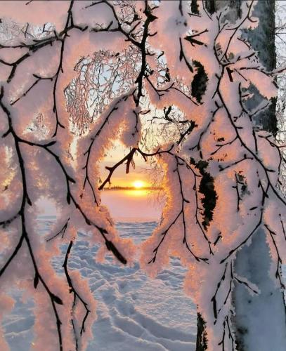 a view of the sunset through a window covered in snow at Suite il sogno di Grebek in Passo del Tonale
