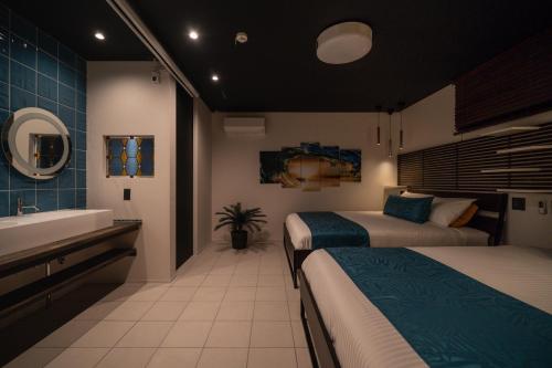 a bedroom with two beds and a sink and a tub at Okinawa Villa KILOHANA in Inbu