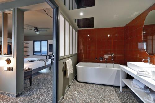 La salle de bains est pourvue d'une baignoire, d'un lavabo et d'un lit. dans l'établissement DINA MORGABINE SAINT DENIS, à Saint-Denis