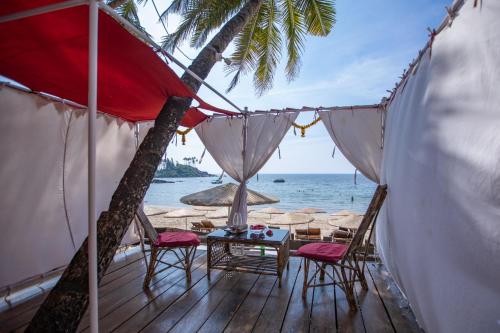 a deck with chairs and a table on the beach at Art Resort Goa in Palolem