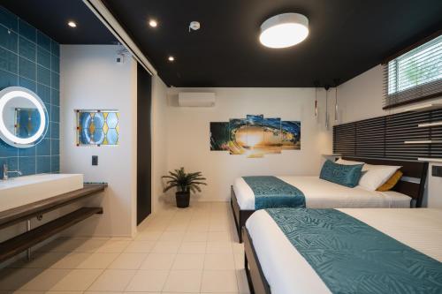 a room with two beds and a sink and a tub at Okinawa Villa KILOHANA in Inbu