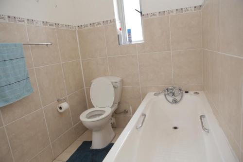 a bathroom with a toilet and a bath tub at Holiday apartment - 2min from beach (Melkbosstrand, Cape Town) in Melkbosstrand