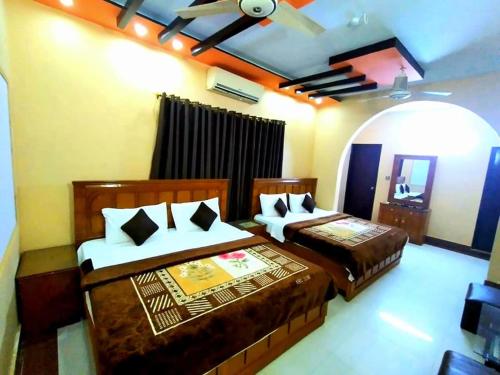 a bedroom with two beds and a ceiling fan at Royal Residency Guest House Karachi in Karachi