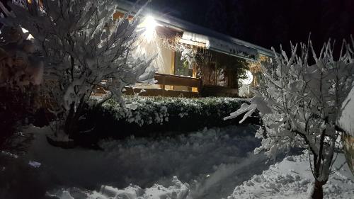 a snow covered yard with a bench in front of a house at Knusperhäuschen Maria Nikoletta in Witra