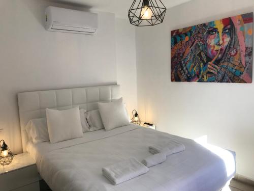 a bedroom with a large white bed with a painting on the wall at Home SEA&DREAMS OldTown I in Calpe