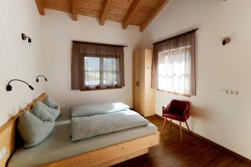 a bedroom with a bed and a red chair at Nestlhof in Vipiteno