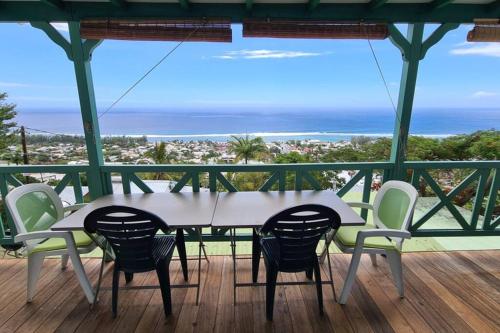 a table and chairs on a balcony with a view of the ocean at Chalet Sunset, vue panoramique sur la baie, proche de Saint-Leu et ses plages in Saint-Leu