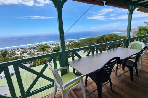 a table and chairs on a balcony with a view of the beach at Chalet Sunset, vue panoramique sur la baie, proche de Saint-Leu et ses plages in Saint-Leu