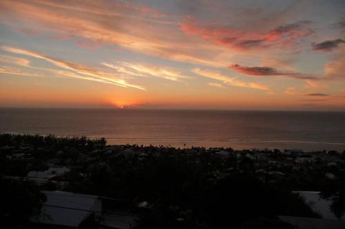 a sunset over the ocean with a city at Chalet Sunset, vue panoramique sur la baie, proche de Saint-Leu et ses plages in Saint-Leu