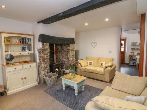 a living room with a couch and a fireplace at Higher Primrose Cottage in Winkleigh