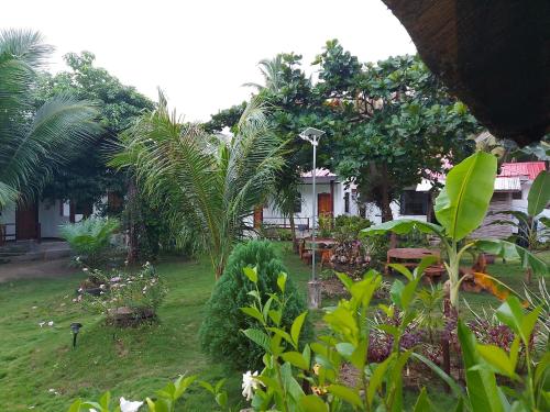 a garden with tables and palm trees in front of a house at Gardenview Homestay Siargao in General Luna