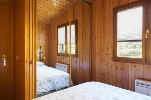 2 camas num quarto de madeira com 2 janelas em El Refugi de les Basses Apartament em Campelles