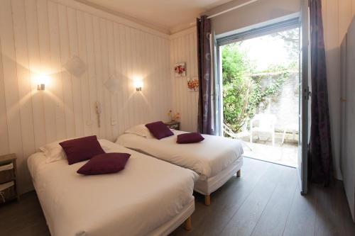 two beds in a room with a large window at Le Pavillon Bleu Hotel Restaurant in Royan