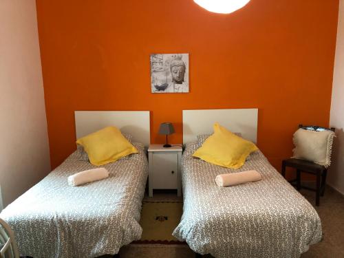 twee bedden in een kamer met oranje muren bij Casa Norb in Teror