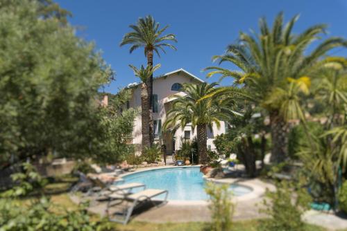 une piscine avec des palmiers et un bâtiment dans l'établissement La Villa Roseraie , Hôtel Familial OUVERT TOUTE L'ANNEE, à Vence