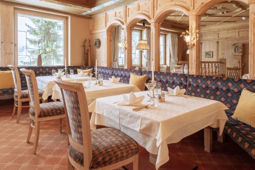 un ristorante con due tavoli, sedie e finestre di Hotel Seelos a Seefeld in Tirol