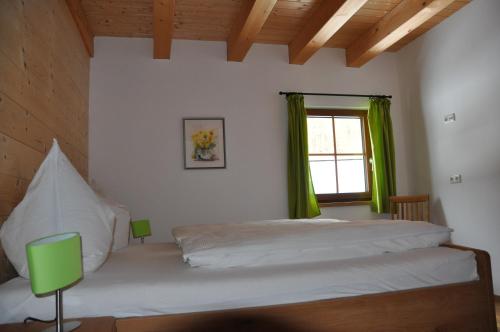 a bedroom with a bed and a window with green curtains at Ferienwohnung Dichtlbauer in Sankt Gilgen