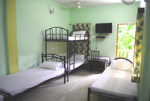 卡蘭古特的住宿－Joe And Marietta's Guesthouse，客房设有两张双层床和电视。