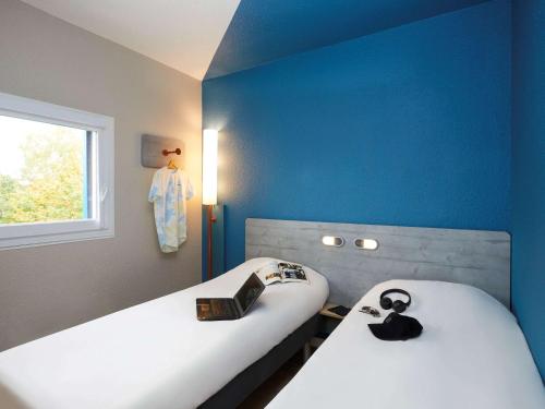 two beds in a room with blue walls at Ibis Budget - Lille Villeneuve D'Ascq in Villeneuve d'Ascq