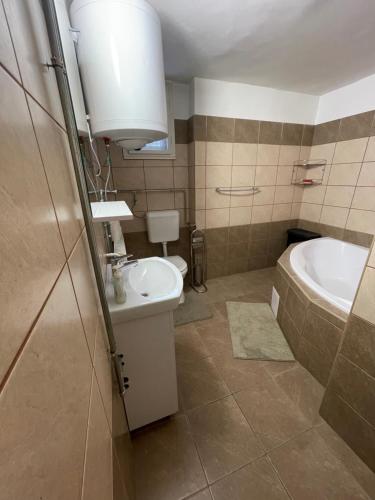 a bathroom with a sink and a tub and a toilet at City Apartman in Nyíregyháza