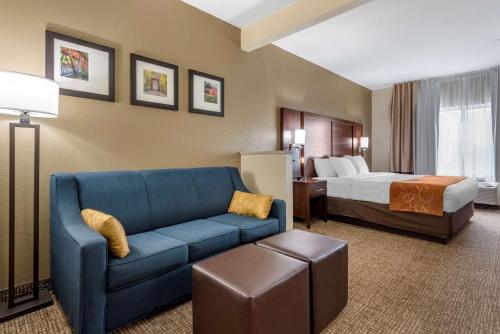 a hotel room with a blue couch and a bed at Comfort Suites Auburn near I-69 in Auburn