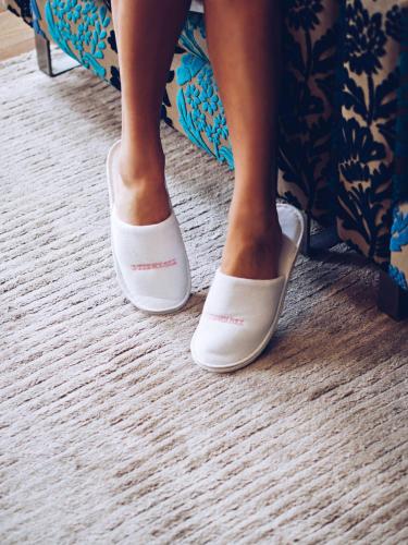 a woman sitting on a bed wearing white shoes at Tigerlily in Edinburgh
