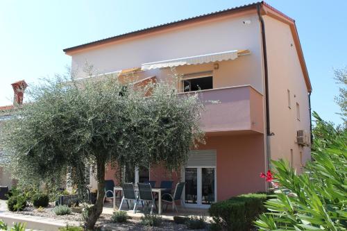 a house with chairs and a tree in front of it at Filipovic Apartmani in Medulin