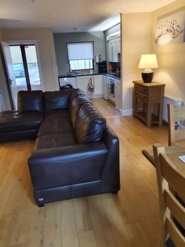 a living room with a black leather couch and a kitchen at Mulranny Suites & Lodges in Mulranny