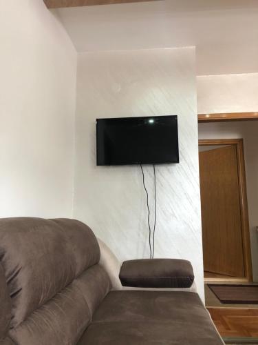 a living room with a couch and a flat screen tv on a wall at Apartman Kosuta B3 in Jahorina