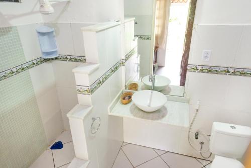a white bathroom with a toilet and a sink at Pousada Luar das Águas in Ilha de Boipeba