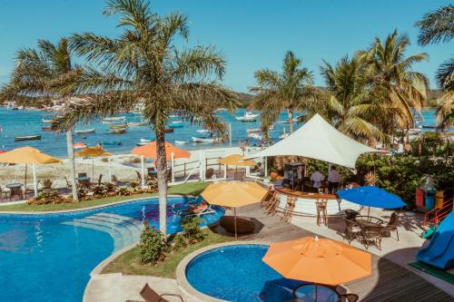 um resort com piscina, mesas e guarda-sóis em Hotel Paradiso del Sol em Cabo Frio