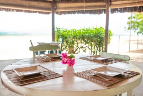 einem Tisch mit zwei Platten und einer rosa Blume darauf in der Unterkunft Pousada Luar das Águas in Ilha de Boipeba