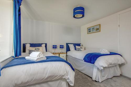 two beds in a room with blue and white at The Barn in Felbrigg