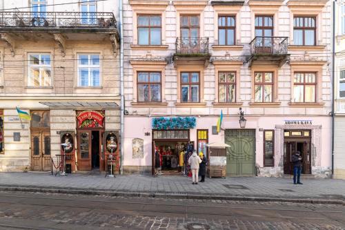 um edifício numa rua com pessoas a andar na frente dele em Rynok Square city center two bedroom apartment! em Lviv
