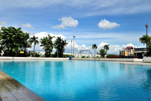 a large swimming pool with a playground and palm trees at Likas Square - KK Spacious Homestay in Kota Kinabalu