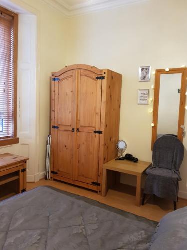 ein Schlafzimmer mit einem Holzschrank und einem Stuhl in der Unterkunft Brucefield Avenue in Dunfermline