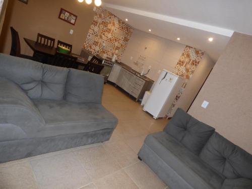 a living room with a couch and a kitchen with a refrigerator at Vila Tamú in Praia do Rosa