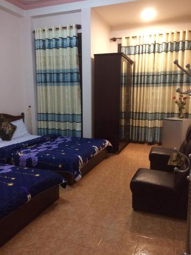 1 dormitorio con 2 camas, silla y cortinas en Hostel Khanh Hương 2, en Da Lat