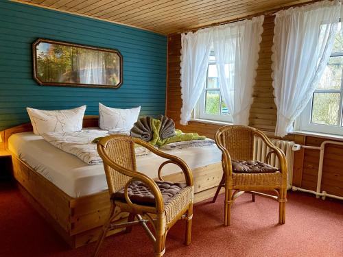 1 Schlafzimmer mit 2 Stühlen, 1 Bett und 2 Fenstern in der Unterkunft Ferienwohnung Kniep in Wernigerode