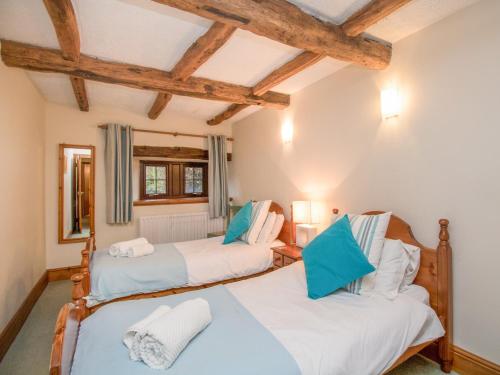 two beds in a room with wooden beams at Riven Oak in Kendal