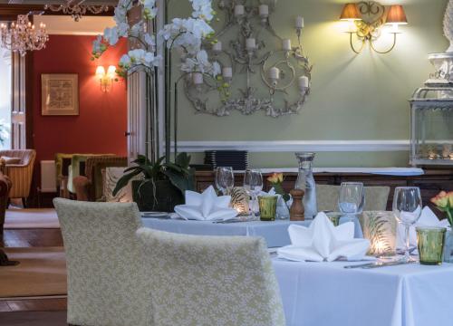 a table in a restaurant with white tables and chairs at The Grasmere Hotel in Grasmere