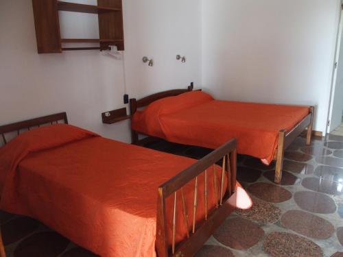 two beds in a room with red sheets at Hotel Buena Vista Se reserva solo con seña in San Gregorio de Polanco