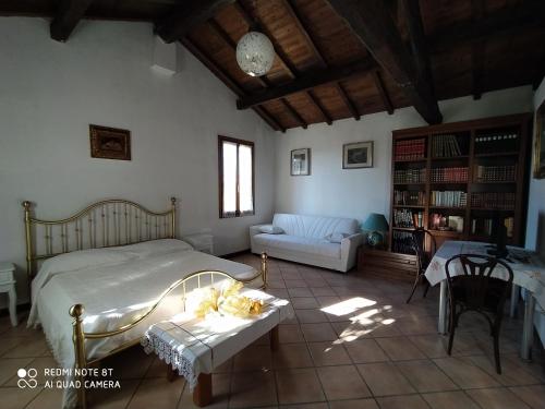 um quarto com uma cama, um sofá e uma mesa em La Rosa Selvatica em Ravarino