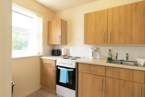 a kitchen with wooden cabinets and a white stove top oven at Studio in Stretford with Great Transport Links in Manchester