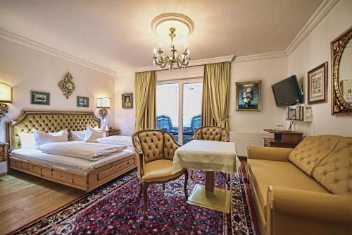 a bedroom with a bed and a table and a couch at Hotel Schloss Fernsteinsee in Nassereith