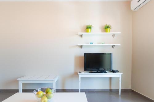 a living room with a tv on a white table at Ntinas Filoxenia Hotel & Spa in Skala Potamias