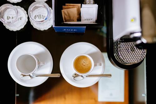 a cup of coffee on a table with two spoons at Grandhotel Pupp in Karlovy Vary