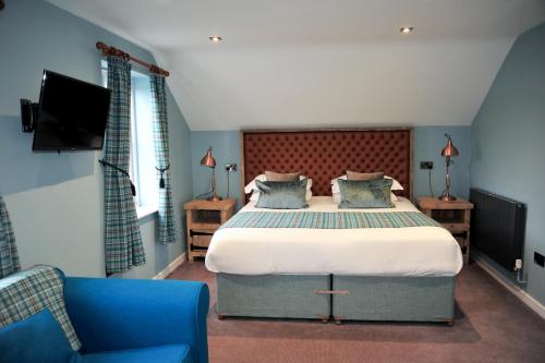 a bedroom with a large bed and a blue chair at The Tal-Y-Cafn Hotel in Tal-y-Cafn