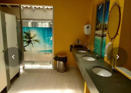 a bathroom with three sinks and a window with a palm tree at Banana Leaf Eco Hostel in Barra de Guaratiba