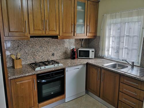 a kitchen with wooden cabinets and a stove and a sink at Casa de Bouças in São Pedro